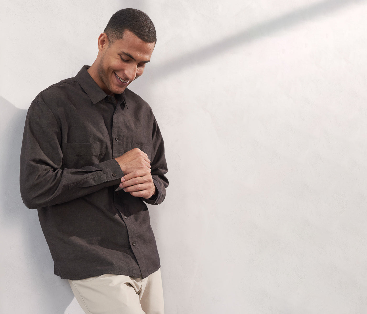 Man wearing a dark brown shirt against a white wall